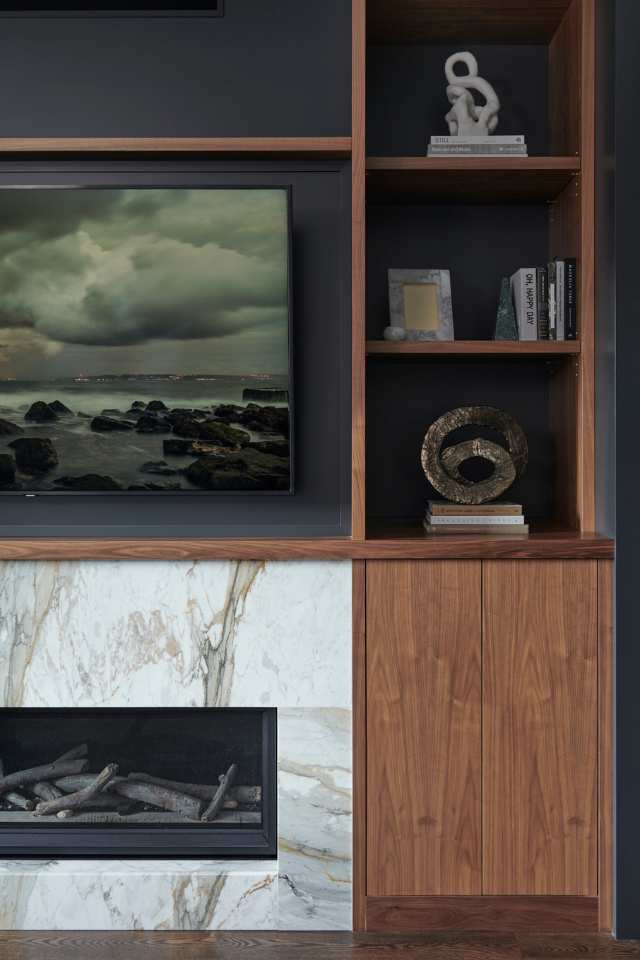 quiet luxury living room with wood shelving and marble fireplace